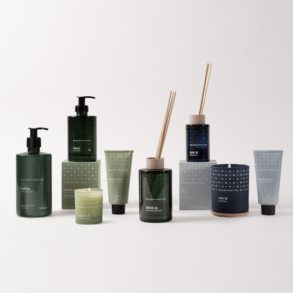 A collection of skincare products, candles, and reed diffusers in green, blue, and neutral tones arranged neatly on a white background.