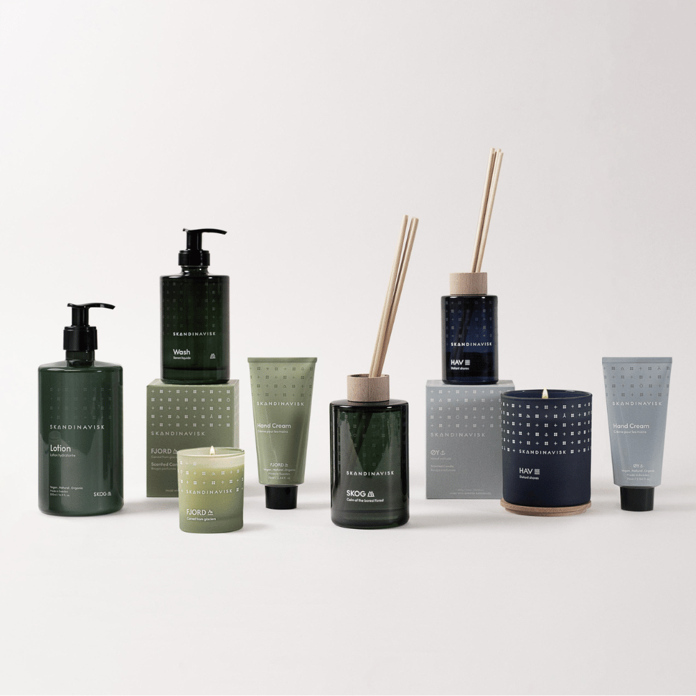 A collection of skincare products, candles, and reed diffusers in green, blue, and neutral tones arranged neatly on a white background.