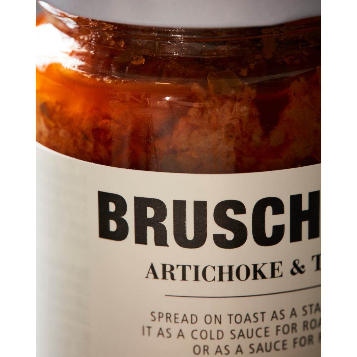 Close-up of a Nicolas Vahé Bruschetta, Artichoke & Tomato jar, showcasing its chunky contents and label with serving suggestions—ideal as a pasta sauce or appetizer.