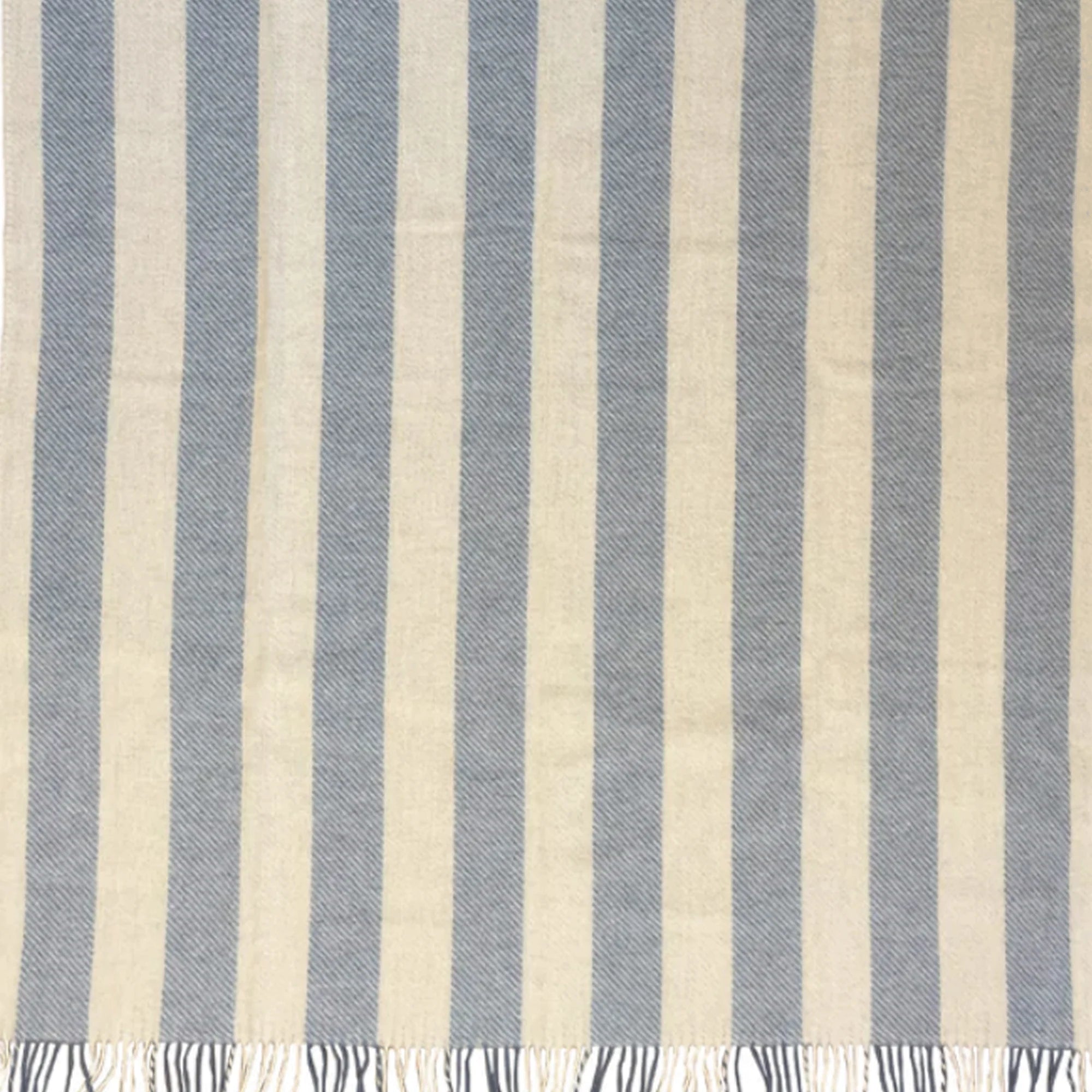 The Klippan Gotland Throw in Vertical Striped Heavenly Blue is crafted from brushed Gotland and lambs wool, featuring alternating light beige and pale blue stripes with small fringes on the bottom edge.