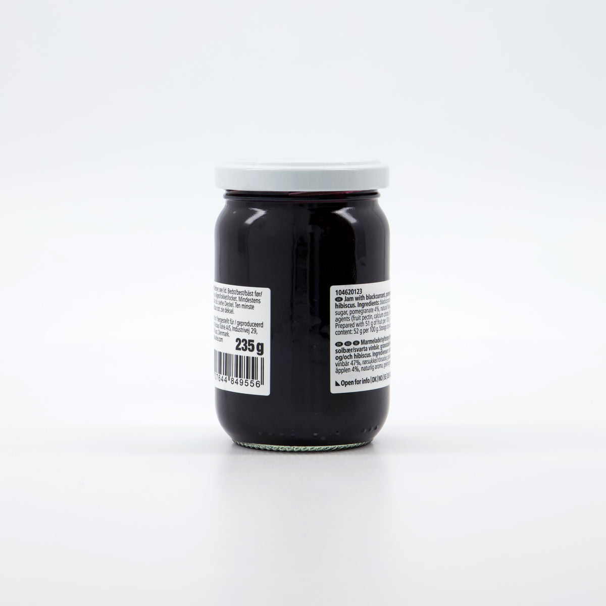 A glass jar of Nicolas Vahé Jam - Blackcurrant & Pomegranate, sealed with a white lid, features product details and a barcode on its label.