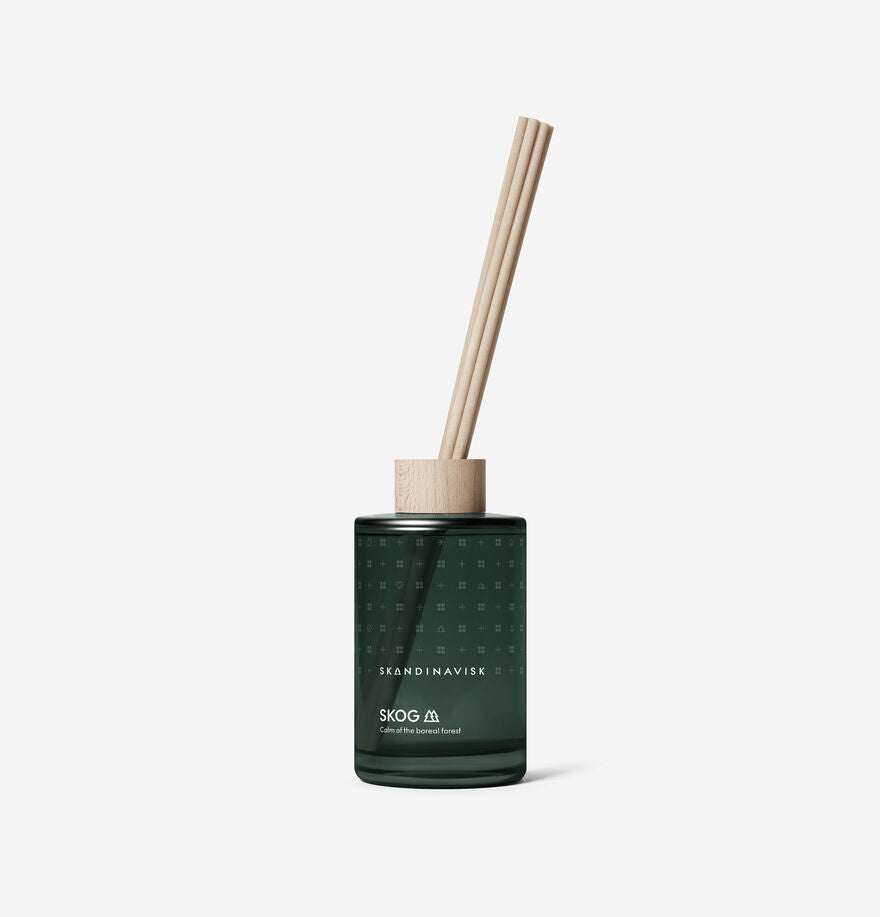 The Scent Diffuser Skog, 200ml by Skandinavisk features a dark green glass bottle with three wooden reeds, evoking a Scandinavian boreal forest fragrance, shown against a plain white background.