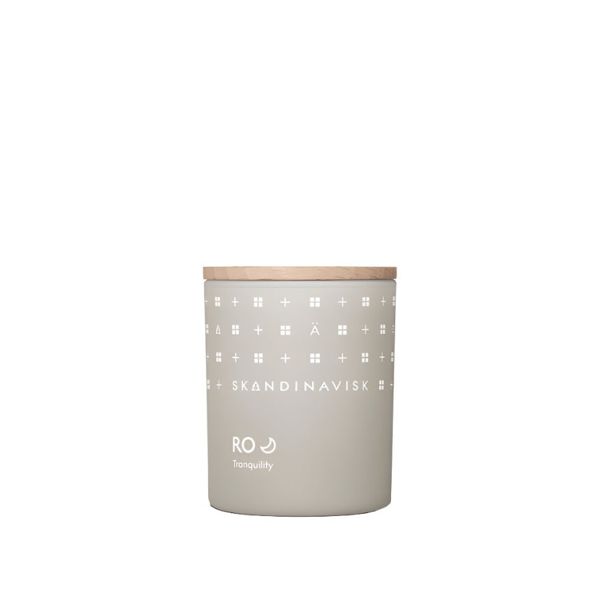 The Skandinavisk Mini Scented Candle Ro 20h, 65g features a beige jar with a wooden lid and white "RO Tranquility" label, crafted from Swedish rapeseed wax for a calming touch.