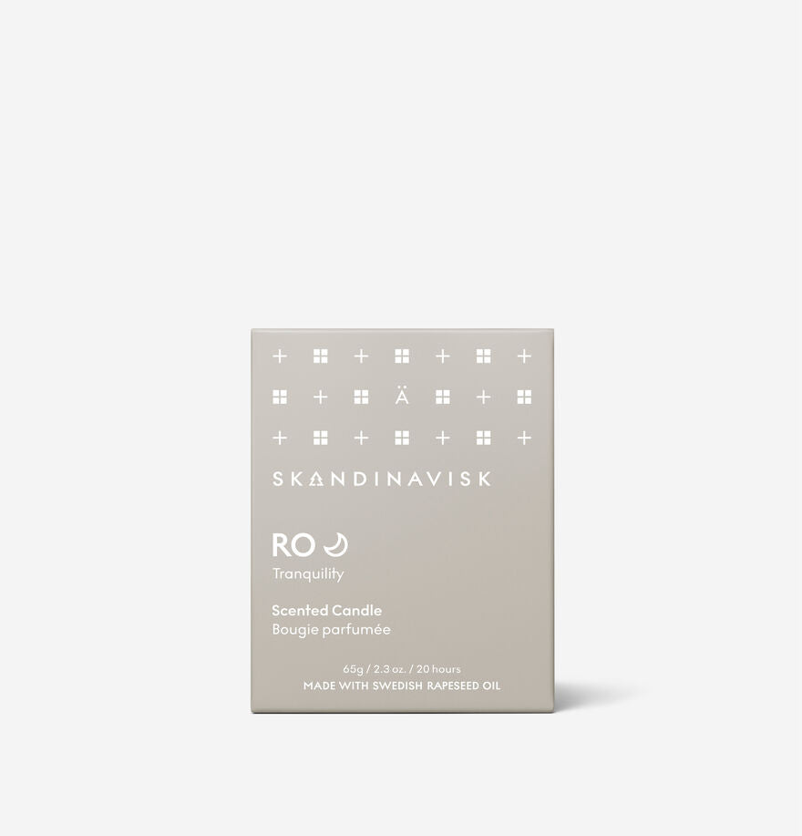 The Skandinavisk Mini Scented Candle Ro 20h, 65g, features calming fragrance, is made with Swedish rapeseed wax, burns for 20 hours, and comes in a beige box with minimalist white text and symbols.
