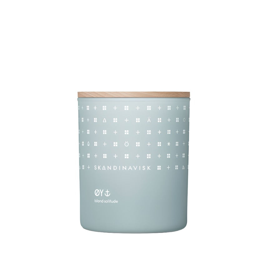 The Skandinavisk Scented Candle Oy 50h, 200g features a light blue jar with white geometric patterns, “SKANDINAVISK” and “ÖY island solitude” text, a wooden lid, and is made from Swedish rapeseed wax.