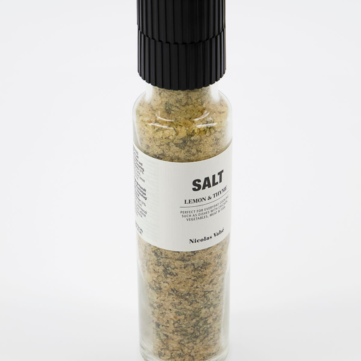 A clear glass grinder of Salt - Lemon & Thyme by Nicolas Vahé, featuring a ceramic grinder top and a white label with product details.