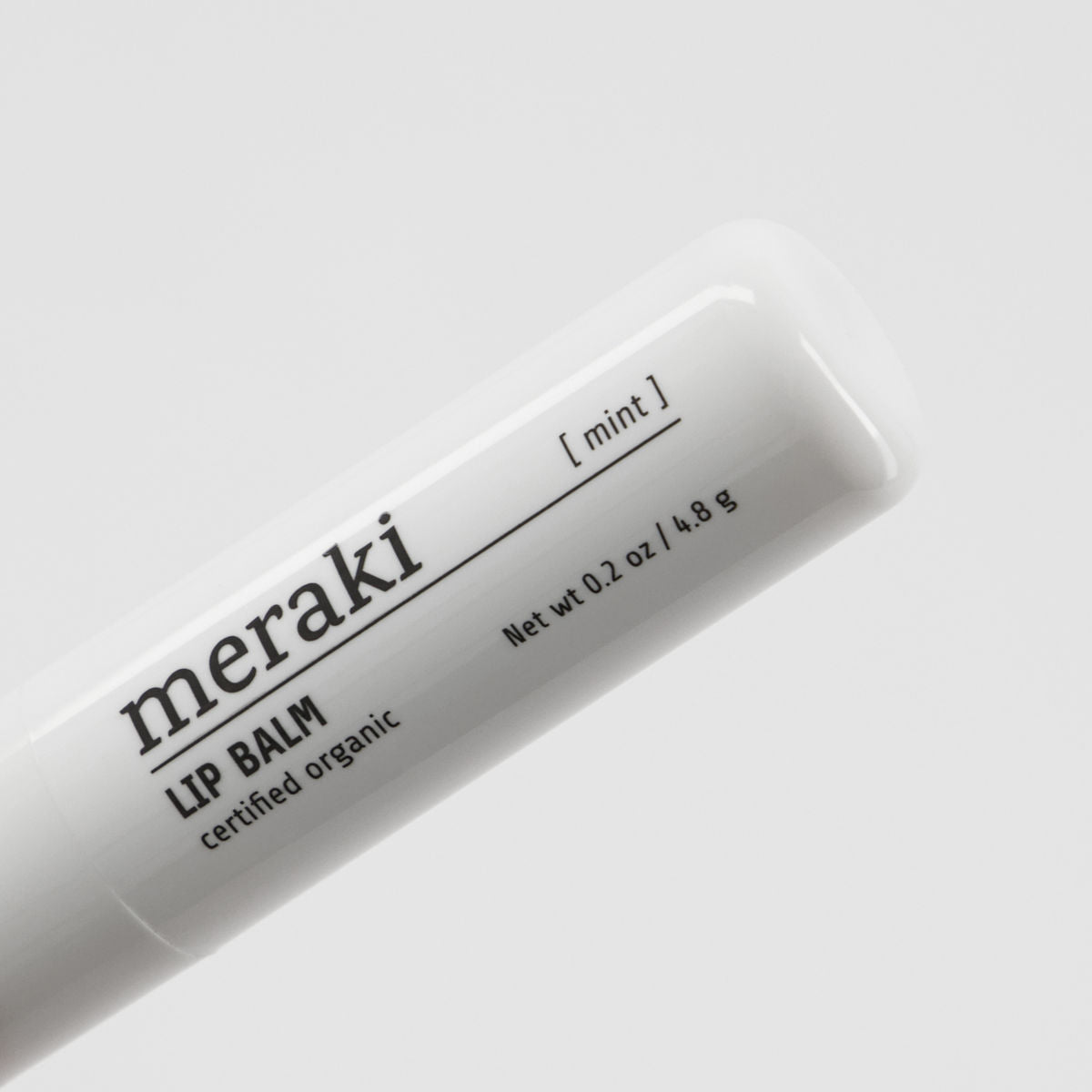 Close-up of a Meraki Organic Lip Balm, Mint—0.2 oz/4.8 g—in a white tube with certified organic labeling, highlighting this nourishing lip balm against a plain background.