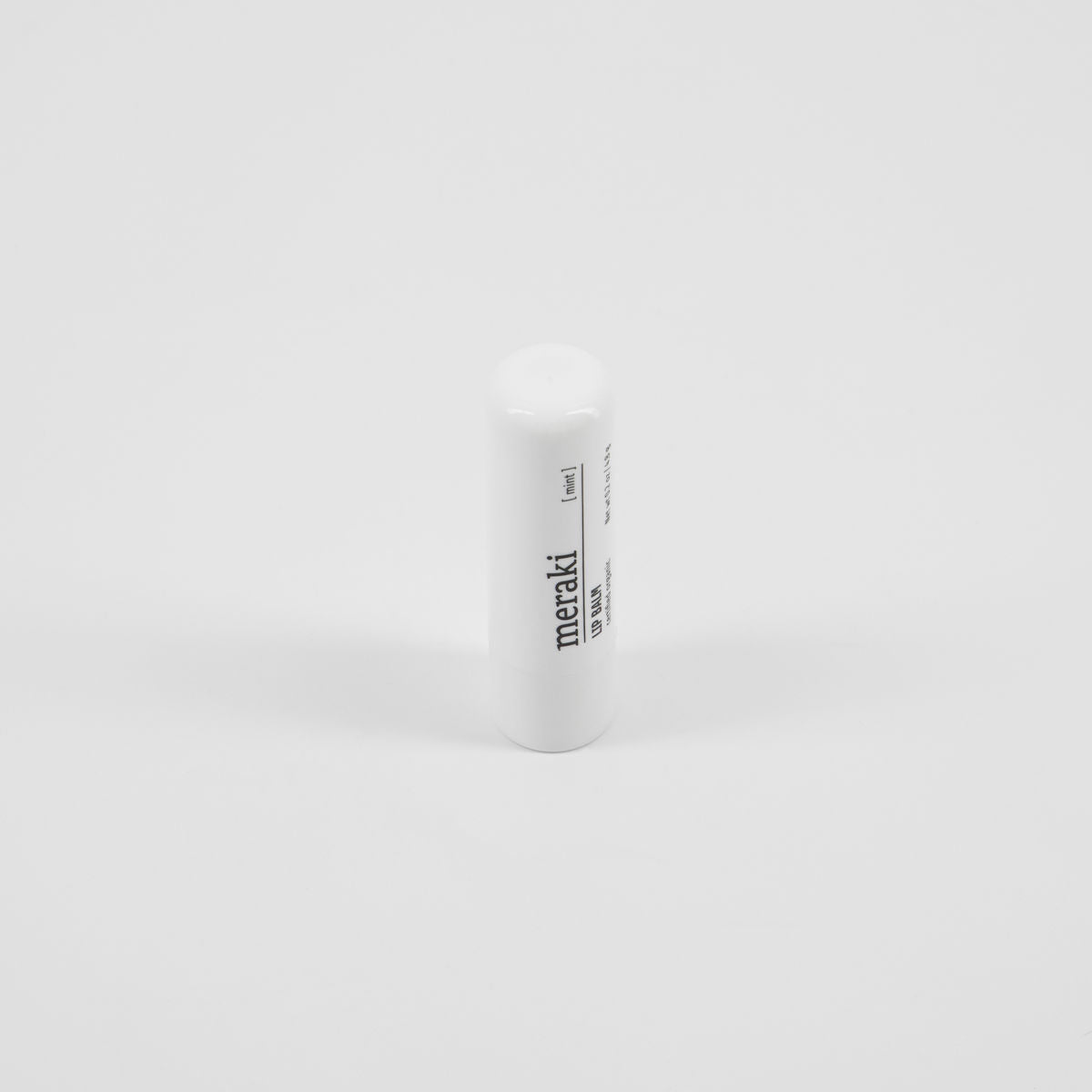 A white cylindrical tube of Meraki Organic Lip Balm, Mint stands upright against a plain white background.