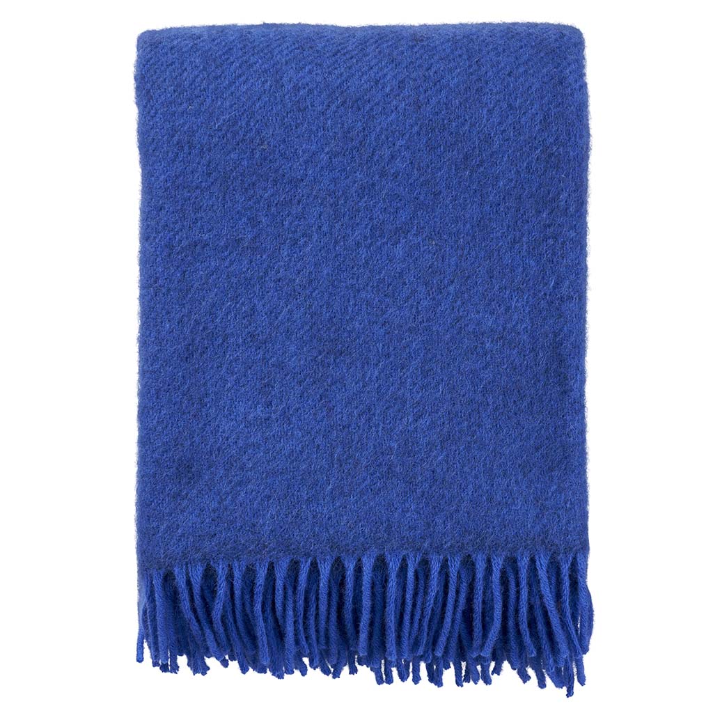 The Gotland Throw in blue by Klippan Yllefabrik is crafted from Gotland wool and lambswool, featuring a folded design with fringe on one edge.
