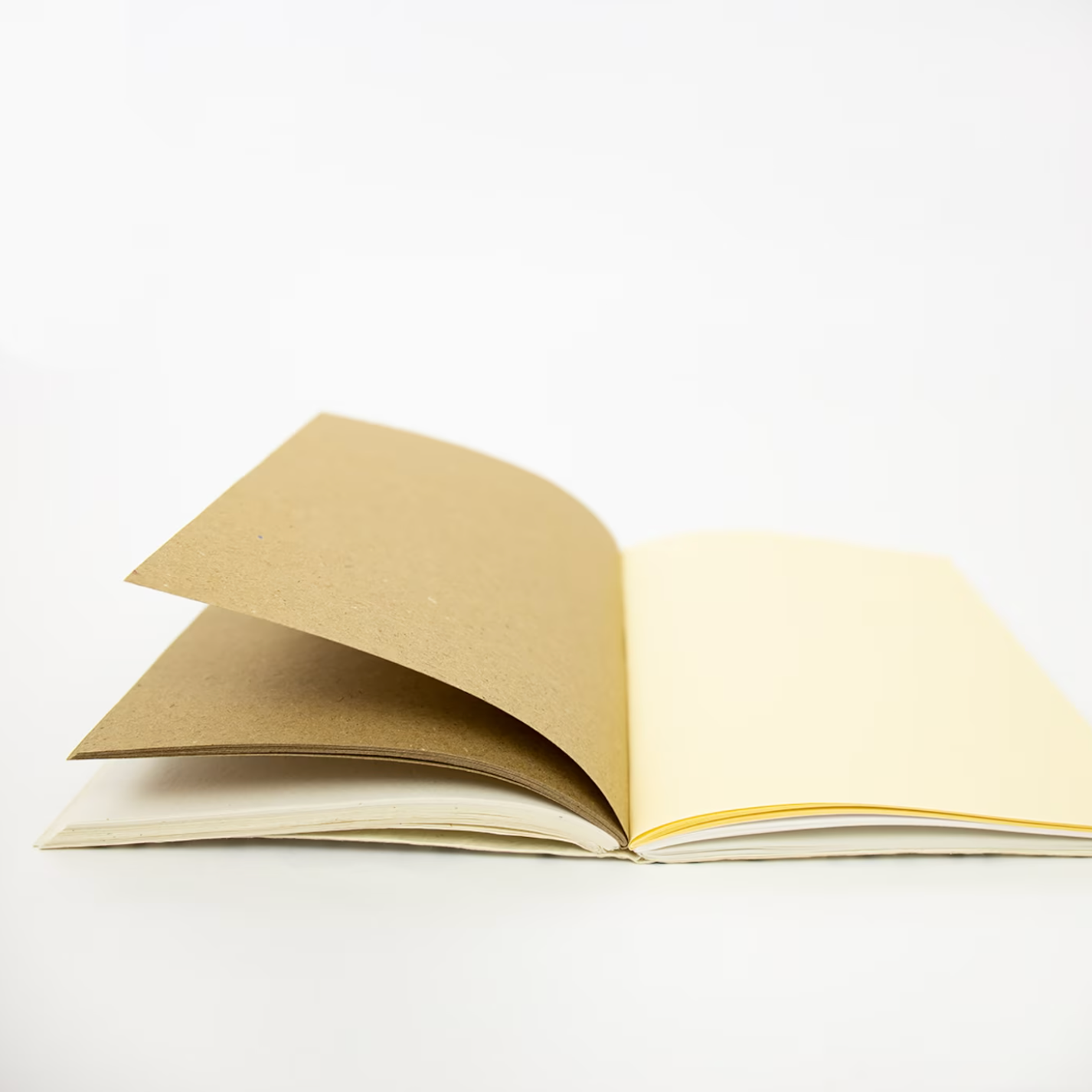 The A World of Craft Dotted Notebook, White, A5 is handmade with eco-friendly cream paper and a brown cover, shown open on a white surface against a plain white background.