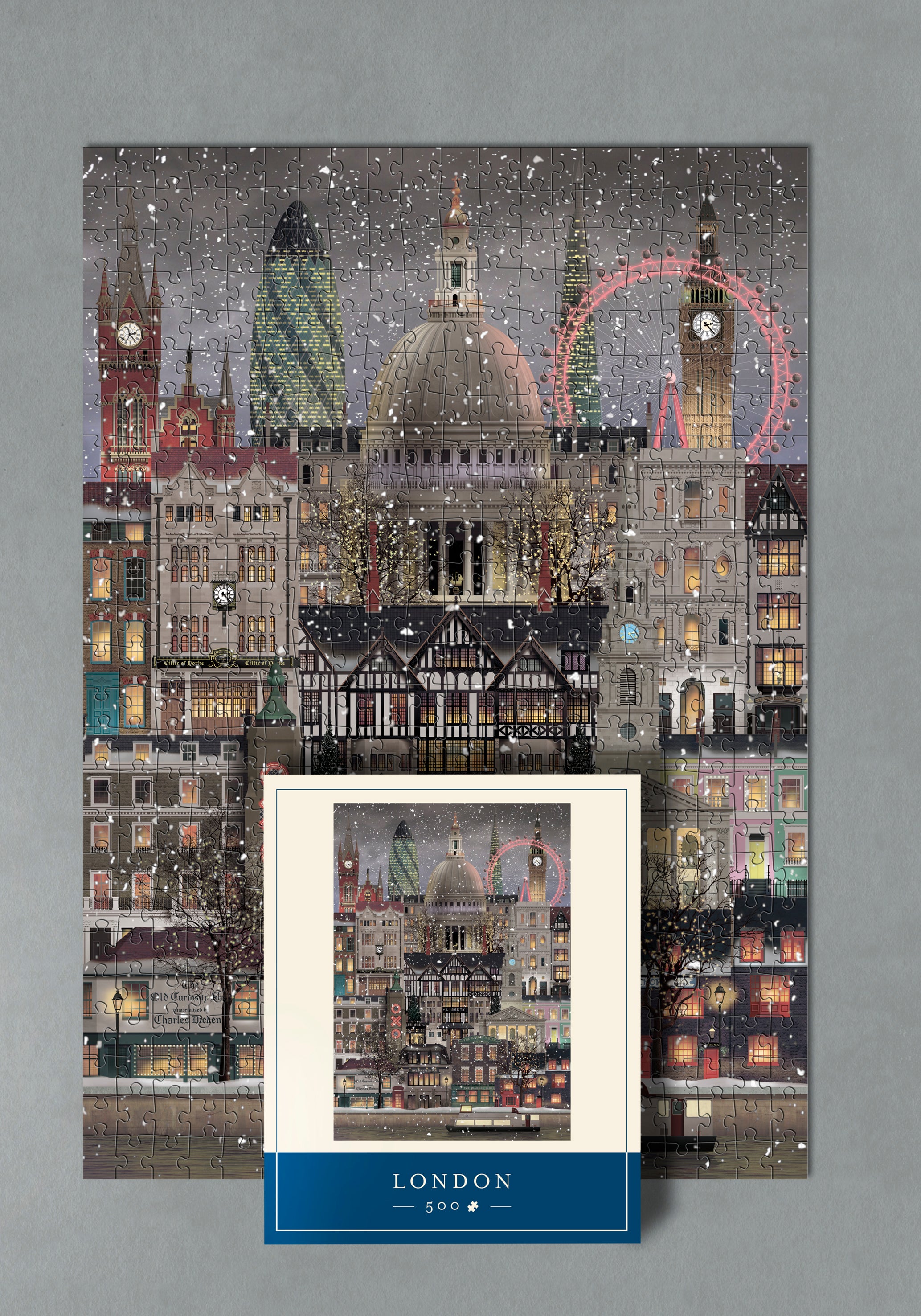 A completed Martin Schwartz Puzzle Christmas in London, 500 Pieces, rests on a gray surface, with its box—featuring the same festive cityscape—placed on top.
