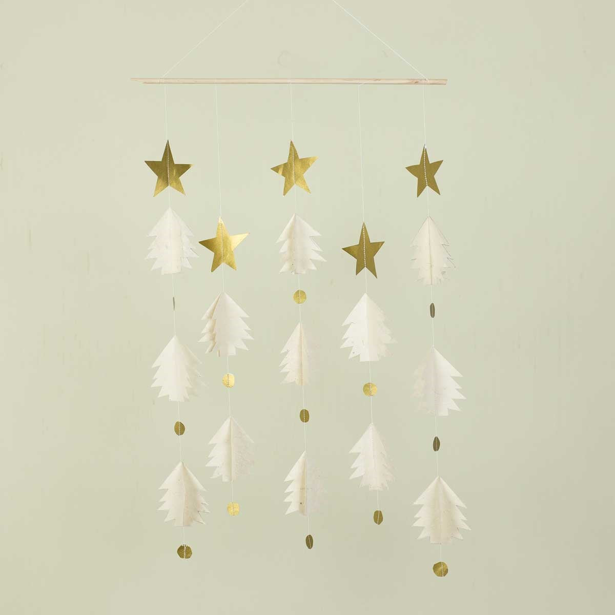 The Christmas Night Mobile in Gold & White by A World of Craft is a handmade festive decoration, featuring gold stars, white paper trees, and shimmering gold circles suspended from strings on a wooden rod. Against a pale background, this minimalist mobile adds subtle elegance and charm to your holiday décor.