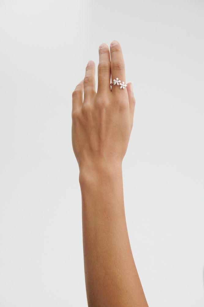 A hand with Pernille Corydon’s Wild Poppy Ring in Silver on the ring finger, featuring a delicate leaf design, extended against a plain white background—a simple yet elegant summer accessory.