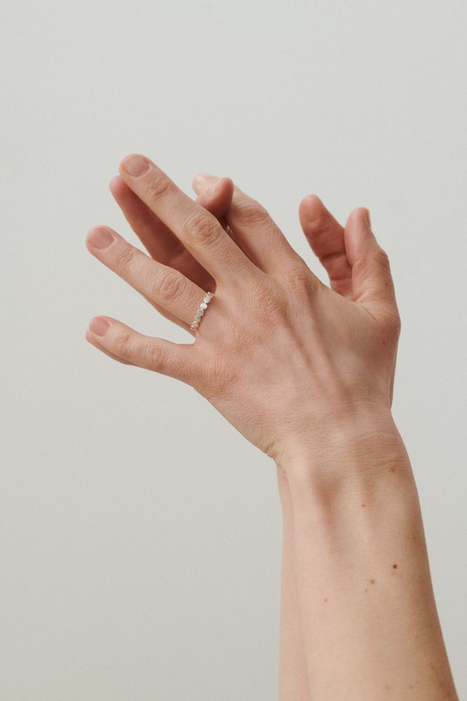 A close-up of two hands, one wearing the Pernille Corydon Catena Ring in Gold on the ring finger, set against a plain light background.