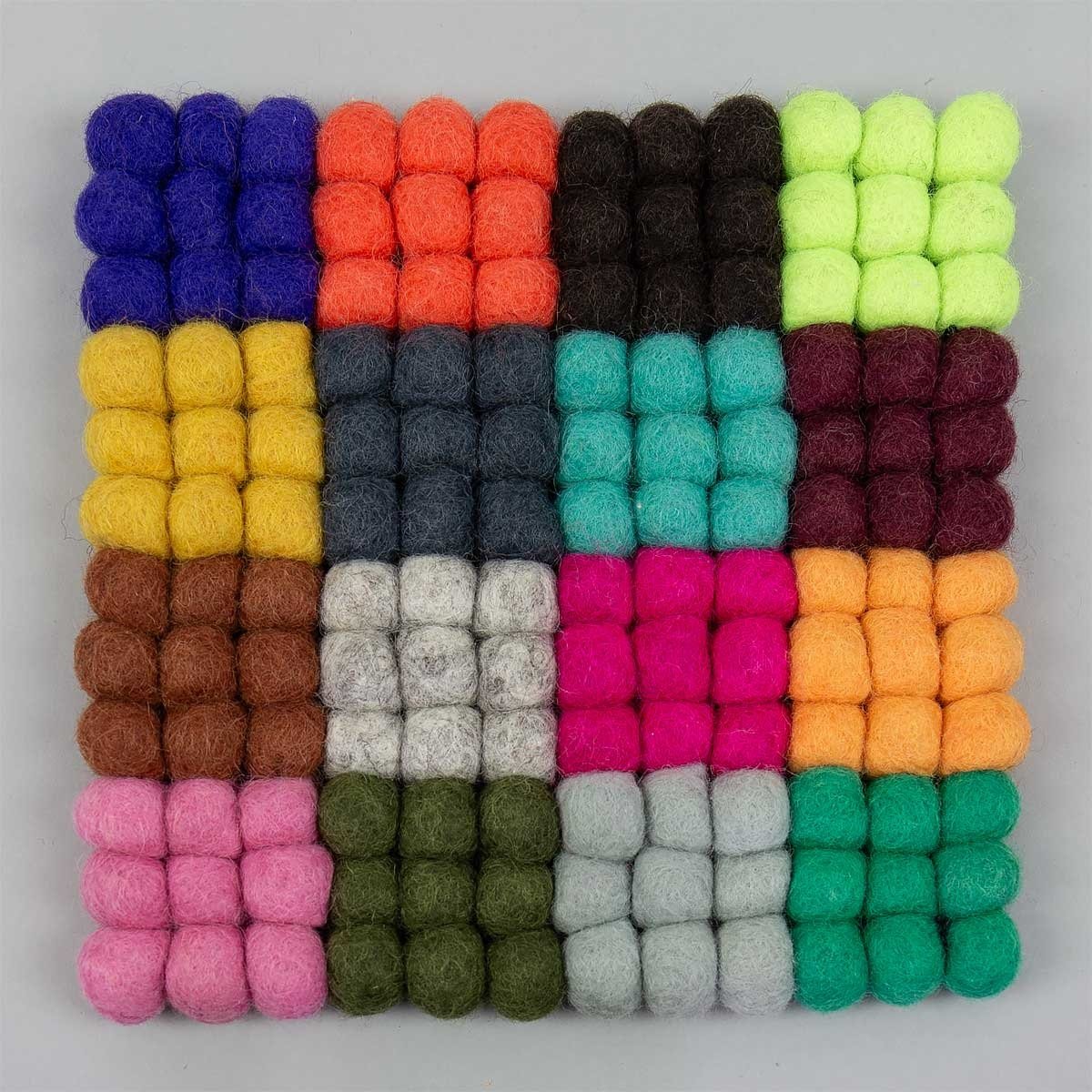 The Natural Wool Pot Holder by A World of Craft features colorful, fair-trade felt balls arranged in a grid—handmade from natural wool for the perfect kitchen accessory.