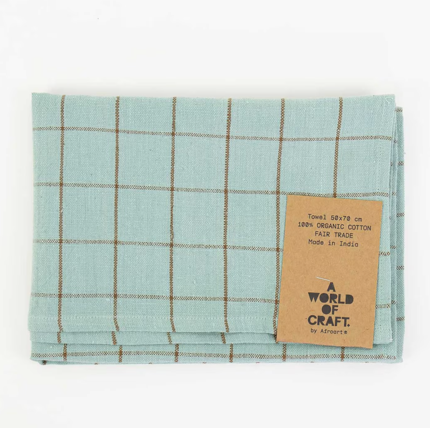 The Eco Grid Tea Towel by A World of Craft is a folded, turquoise and brown hand-woven organic cotton towel with a checkered pattern and a tag listing its size, fair trade certification, and Indian origin.