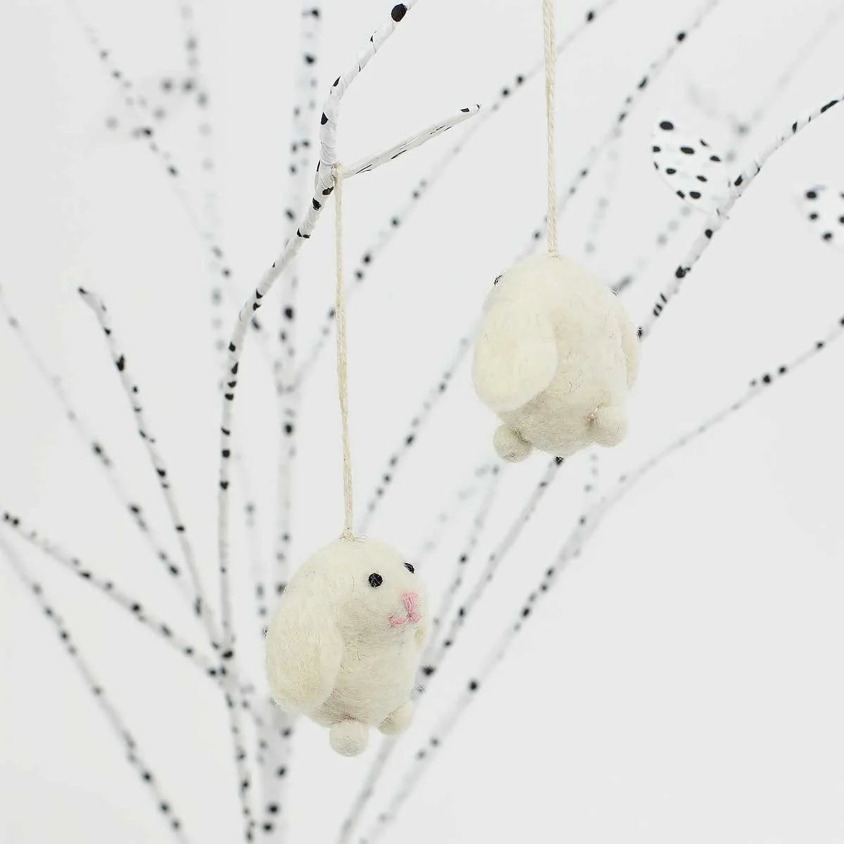 The Mini Easter Bunnies, set of 2 by A World of Craft, feature small handmade white wool bunnies with pink noses hanging from strings—perfect Easter tree decorations for any setting.