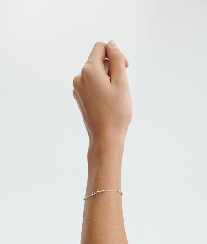 A hand with a light skin tone is raised against a plain white background, adorned with the elegant Pernille Corydon Caia Bracelet in Silver on the wrist.