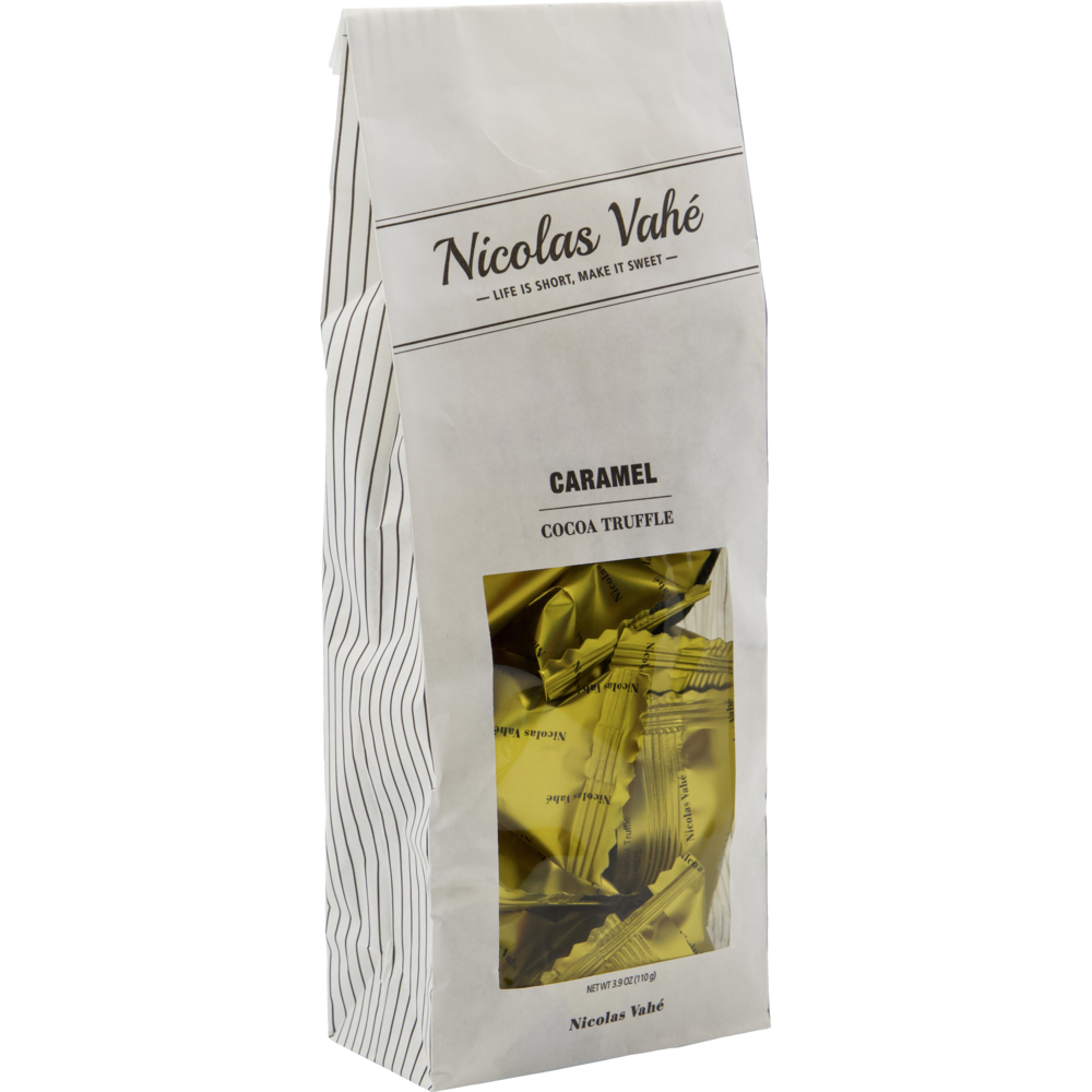 A white, striped paper bag labeled "Nicolas Vahé Cocoa Truffle, Caramel" features a clear window revealing gold-wrapped caramel cocoa truffles inside.