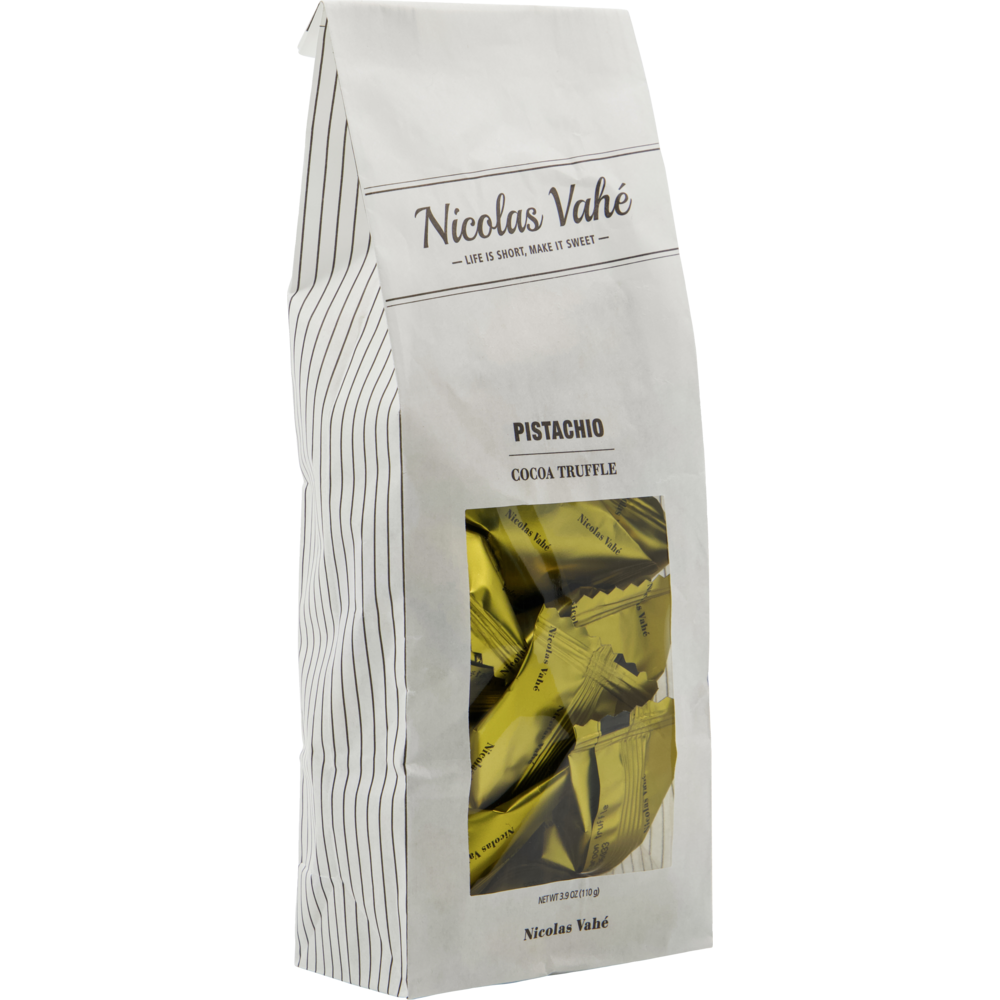 A white bag labeled "Cocoa Truffle, Pistachio" from Nicolas Vahé, showcasing gold-wrapped cocoa truffles through a clear front window—evoking the indulgent flavors of traditional pistachio and almond meringue treats.