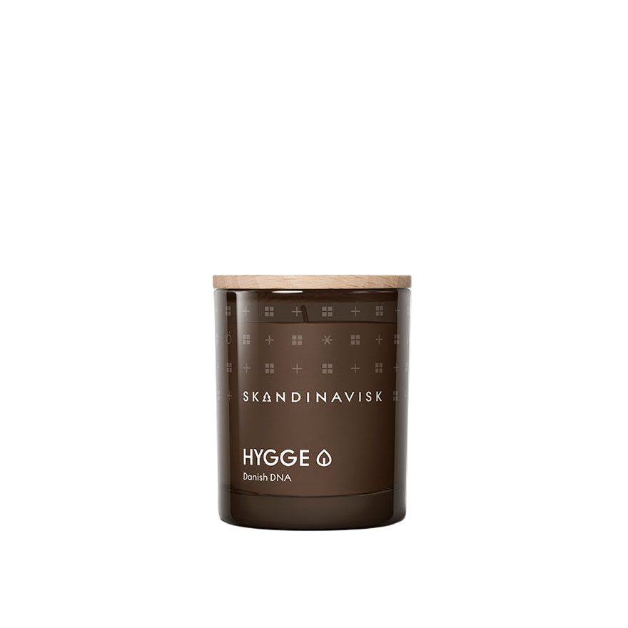 The Skandinavisk Mini Scented Candle Hygge 20h, 65g features brown glass and a wooden lid, crafted with Swedish rapeseed wax. Presented on a plain white background, it embodies Danish hygge in both scent and design.