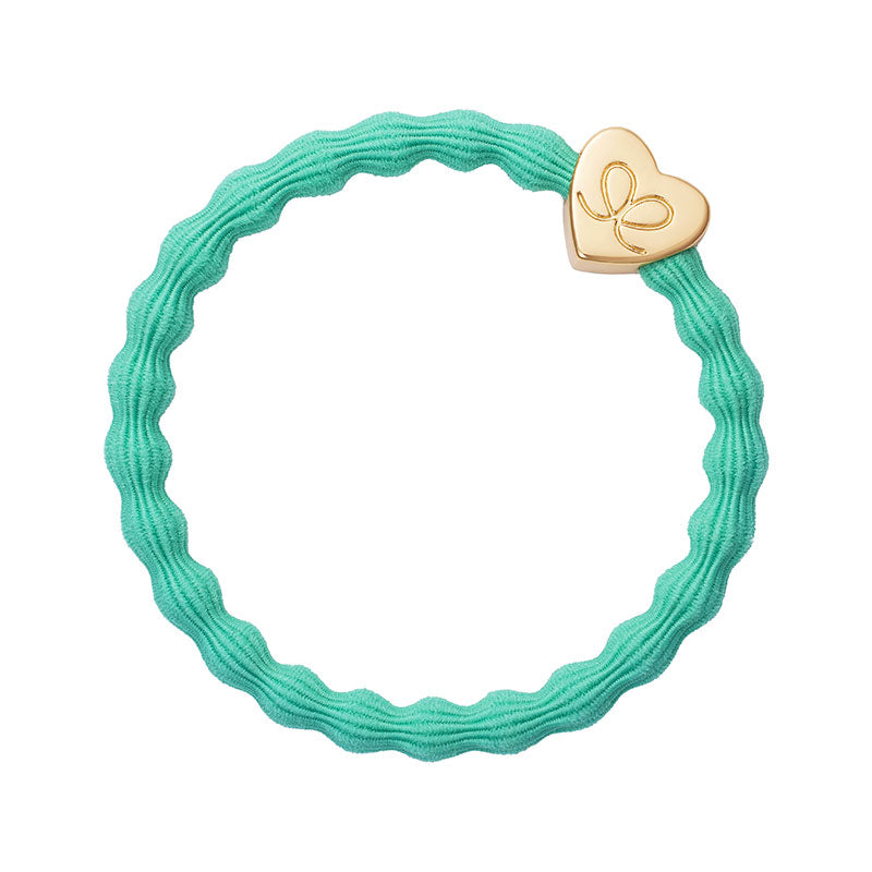 The ByEloise Bangle Band in Jungle Green features a gold, heart-shaped charm with a delicate design, shown on a white background. This wavy elastic hairband doubles as a cute bracelet accessory.