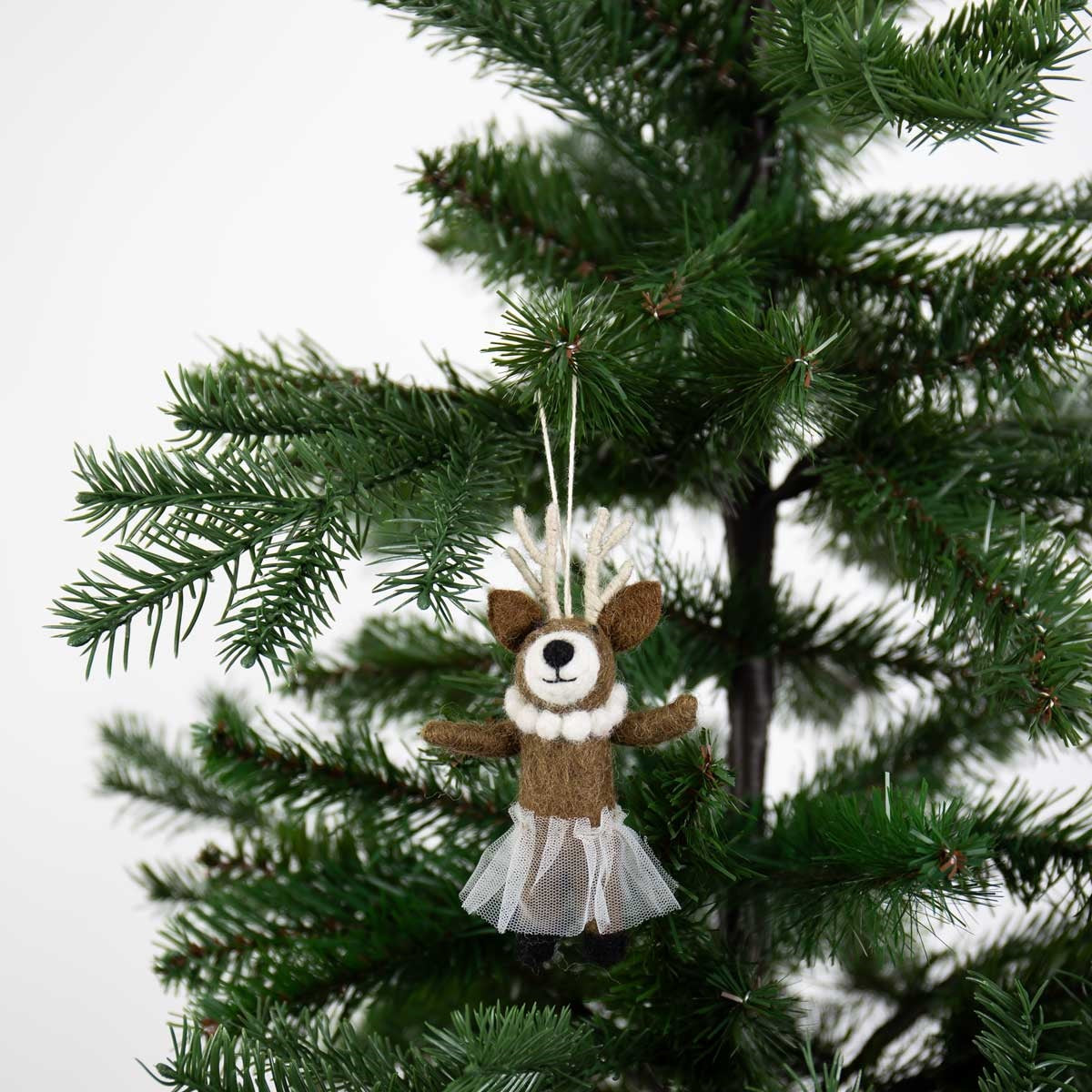 A Deer with Necklace Christmas Ornament by A World of Craft, featuring a handmade felted reindeer wearing a white necklace and a sheer skirt as a ballerina hanging on a Christmas tree.
