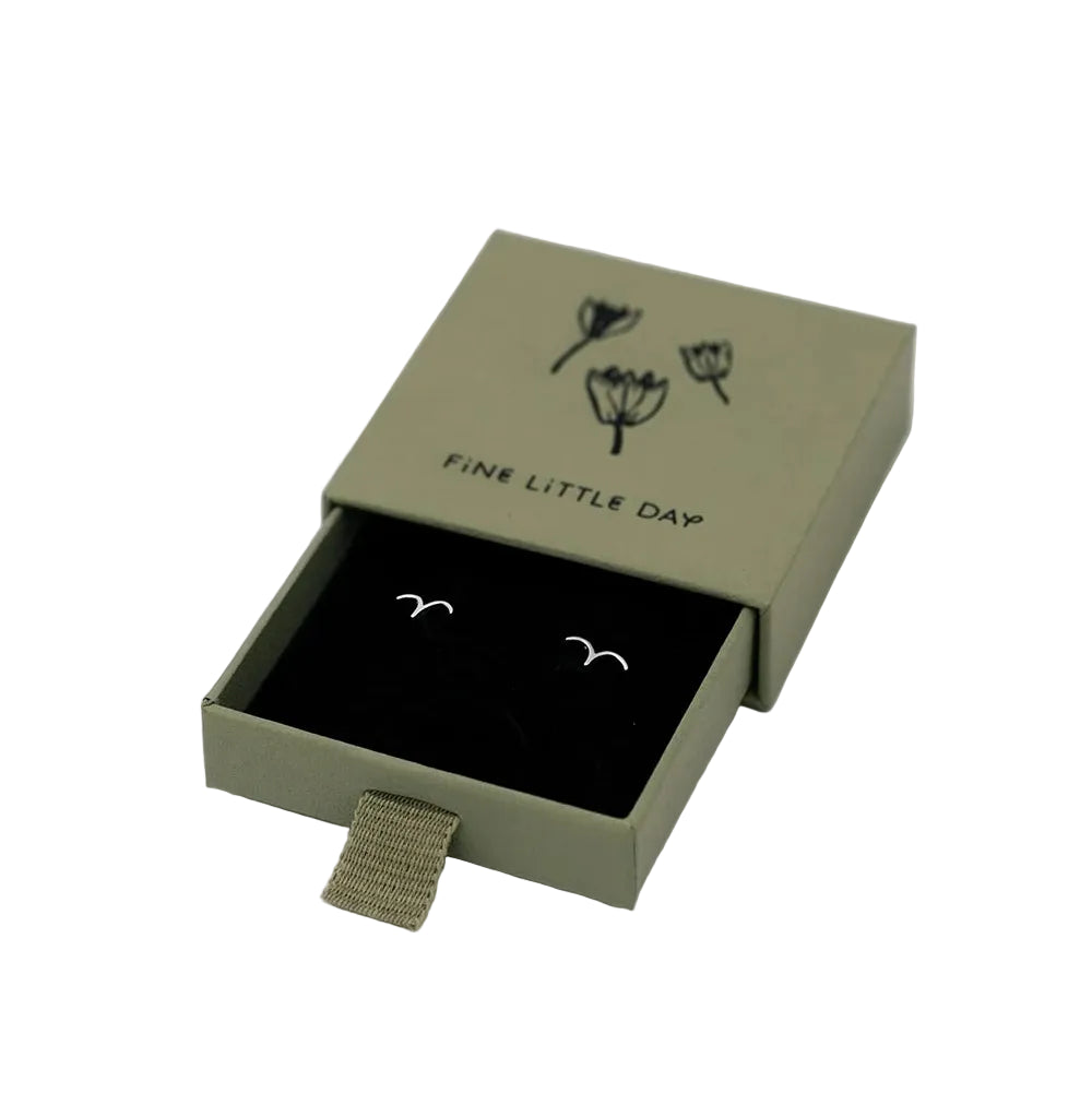 A compact green box labeled “Fine Little Day” contains a pair of Bird Stud Earrings in Silver, featuring a minimalist flying bird design crafted from recycled sterling silver.