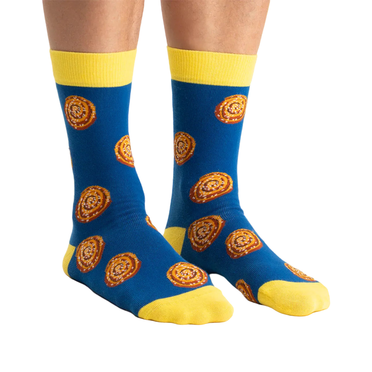 A pair of Svensk Husman Socks—Cinnamon Bun style—features blue socks with yellow toes, heels, and cuffs, adorned with a cinnamon roll pattern. Perfect for adding cozy Swedish fika vibes to your day.