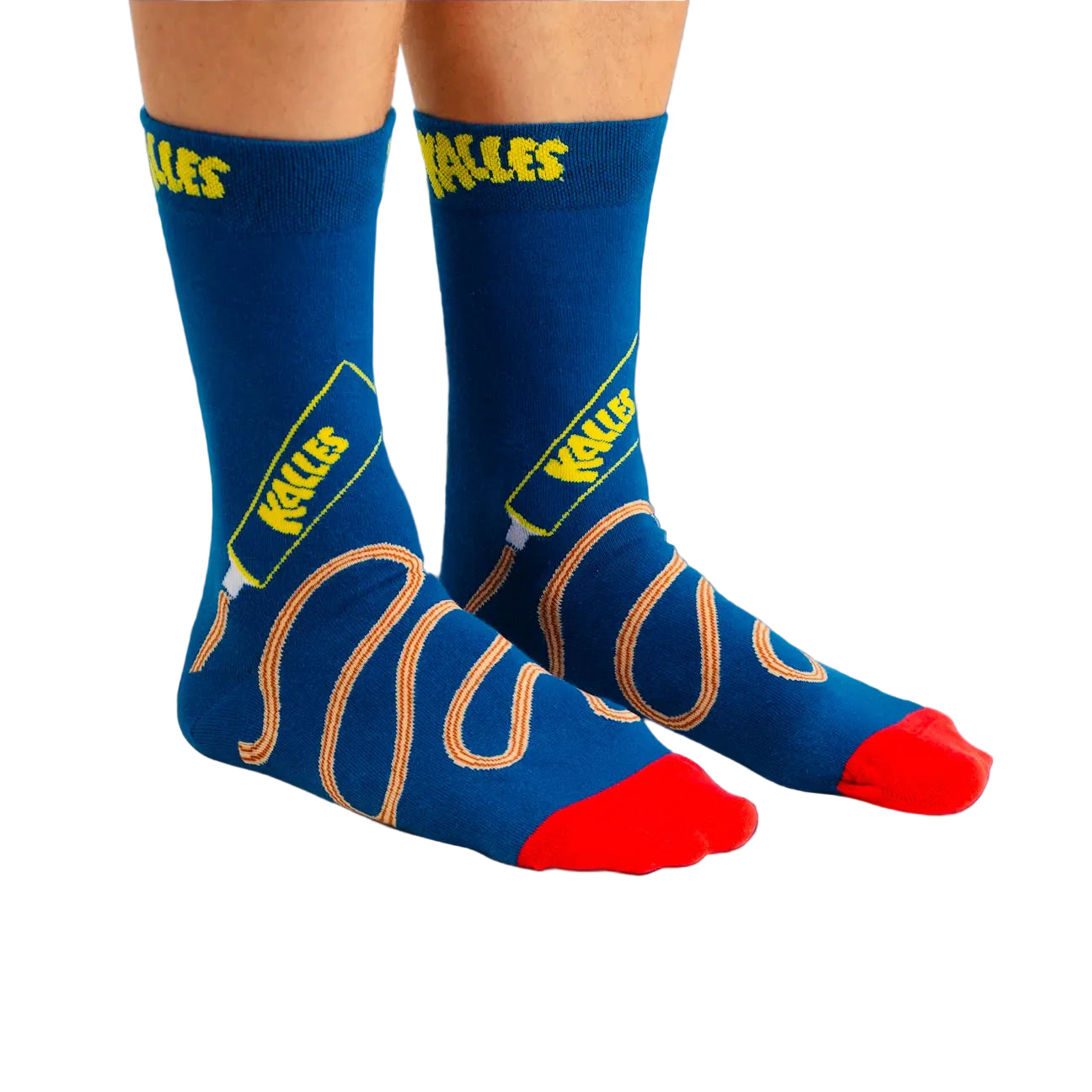 A person wears blue Svensk Husman Socks, Kalles Caviar The Original Special Edition, with red toes and "HEELS" in yellow at the top, featuring a playful tan line design winding up from the toe to the calf.