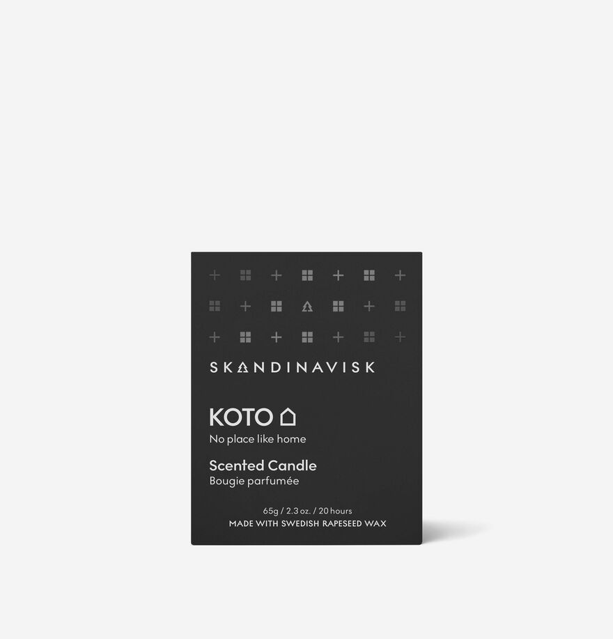 The Skandinavisk Mini Scented Candle Koto 20h (65g) comes in a black box with white text and geometric symbols, featuring the phrase “No place like home” and is made with Swedish rapeseed wax for a cozy Nordic fragrance.