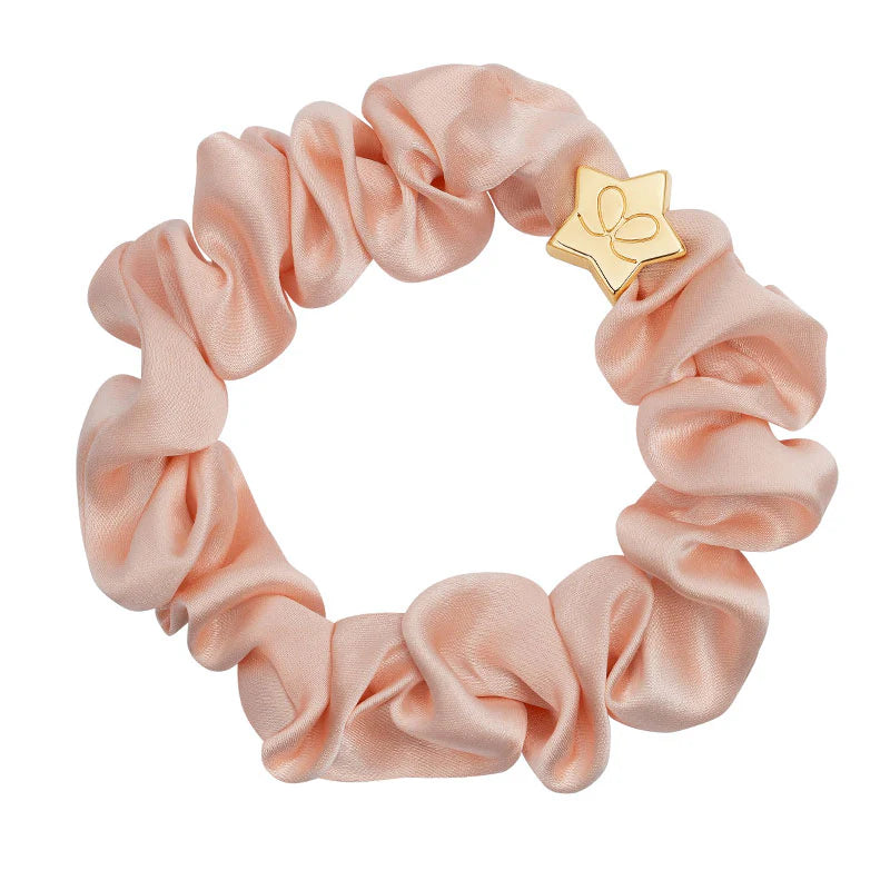 The ByEloise Silk Scrunchie in Powder Pink features a gold star charm engraved with a minimalist leaf design—an elegant hair accessory for any occasion.