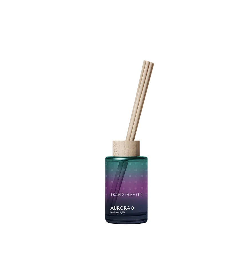 A reed diffuser bottle with a gradient teal, purple, and navy glass body, featuring a light natural wood cap and two light wood reeds, on a clean white background.