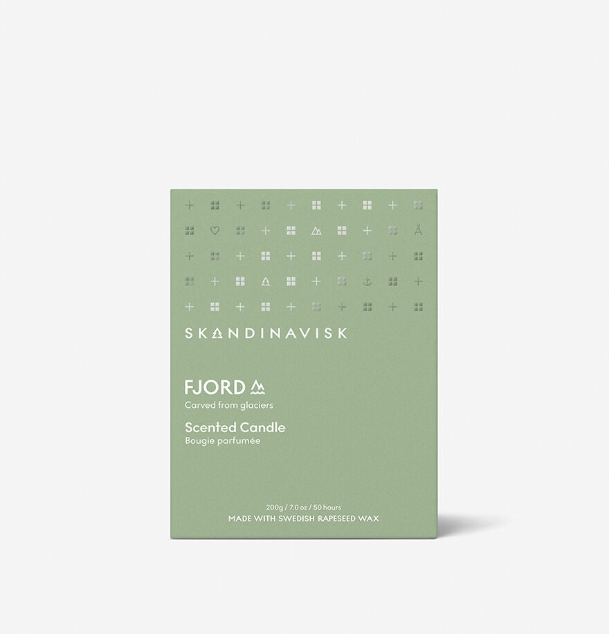 A green Skandinavisk Scented Candle Fjord 50h, 200g features minimal white text and glacier-inspired symbols on painted glass. Crafted with Swedish rapeseed wax for a cleaner, natural burn.