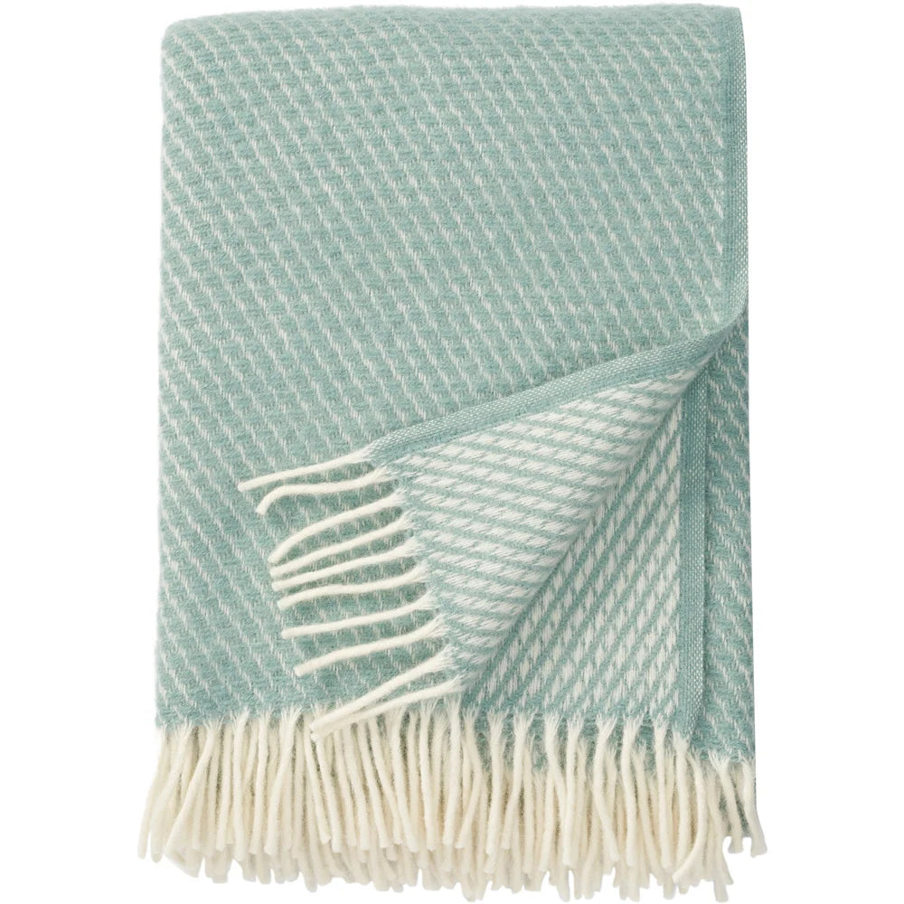 A Velvet Duck Egg Blue Brushed Lambswool Throw by Klippan Yllefabrik, featuring a subtle diagonal pattern and fringed edges, is shown folded against a white background.