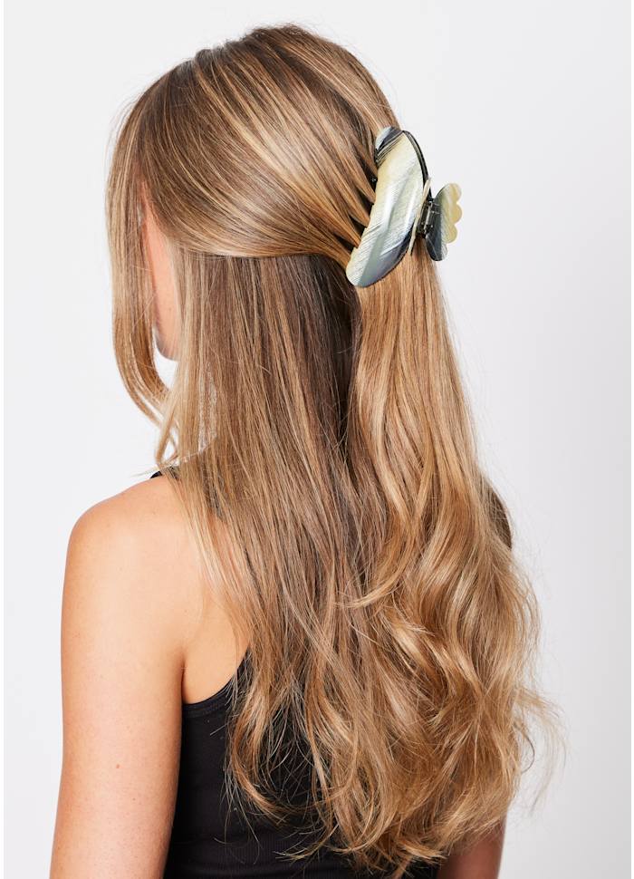 A large black and beige Sui Ava Helle Night Big Hair Claw Clip securing a section of hair at the back of a woman’s head.