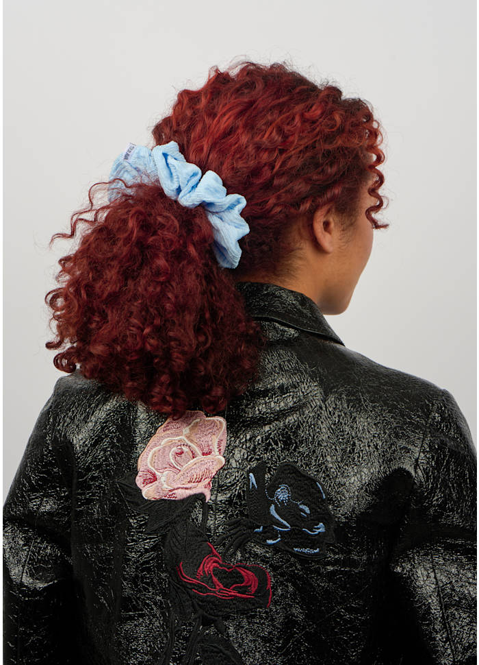A light blue Ea Zig-Zag Scrunchie, Sky Blue, in a ponytail.