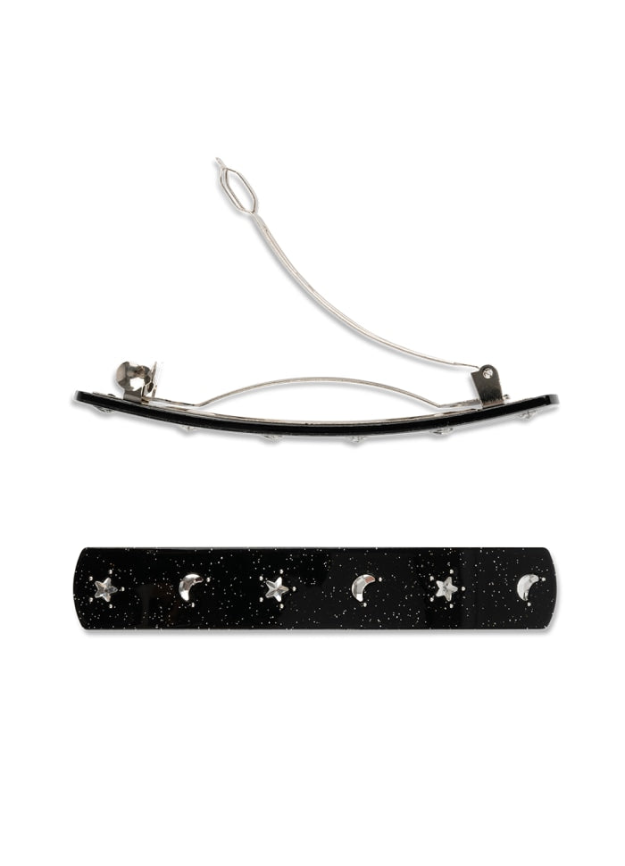 A black, speckled Sui Ava Hair Clip Noel in Black and Rhinestones decorated with alternating silver-tone crescent moon and star charms.