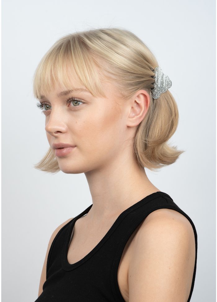 A person with blonde hair wearing a silver glitter Sui Ava Lene Glitter Mini Hair Claw Clip.