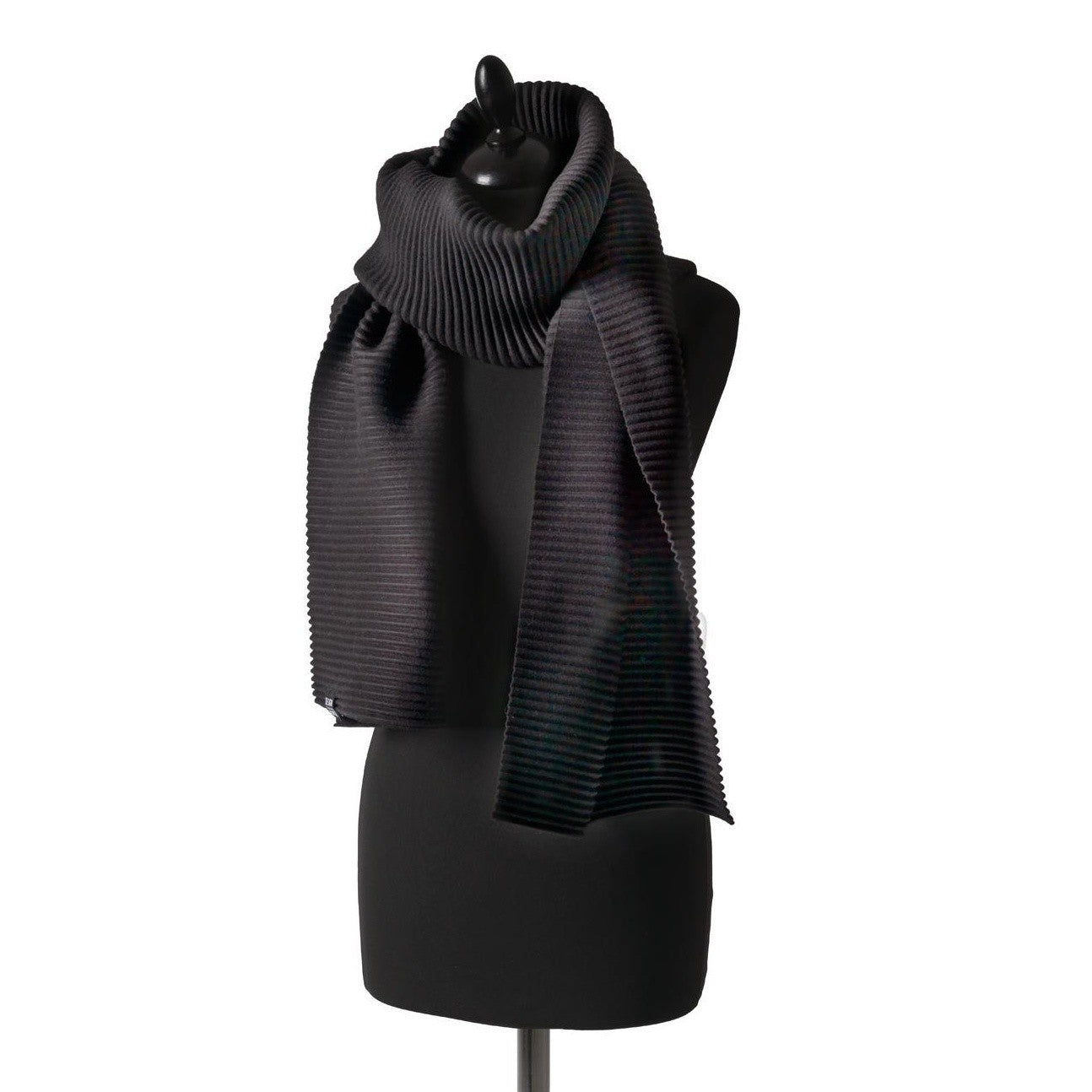 The Pleece Scarf Long in Black by Design House Stockholm, made from pleated fleece, is displayed draped over a black dress form mannequin against a plain white background.