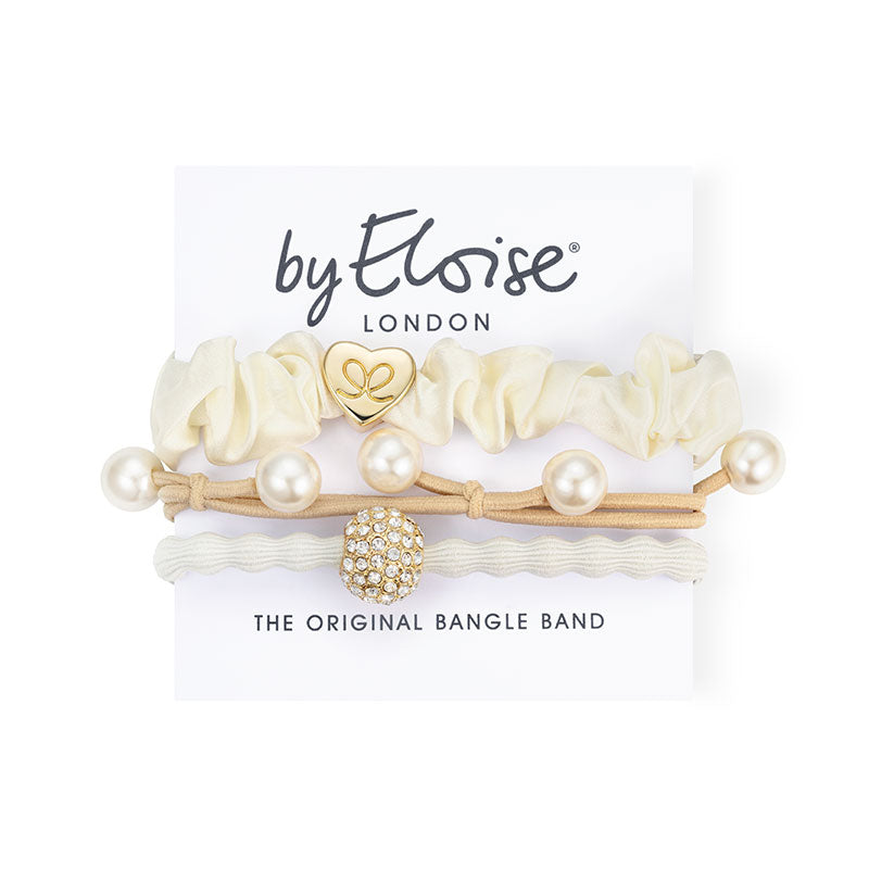 The ByEloise Bangle Band White Party Set includes three chic hairbands with pearls, a gold heart charm, and a rhinestone bead, all presented on a branded card.