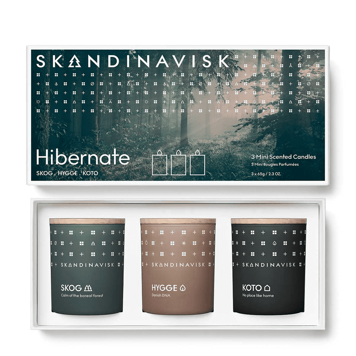 The Skandinavisk Scented Candle Hibernate Mini Giftset includes SKOG, KOTO, and HYGGE candles made from Swedish rapeseed wax, presented in forest-themed packaging labeled 'Hibernate.'.