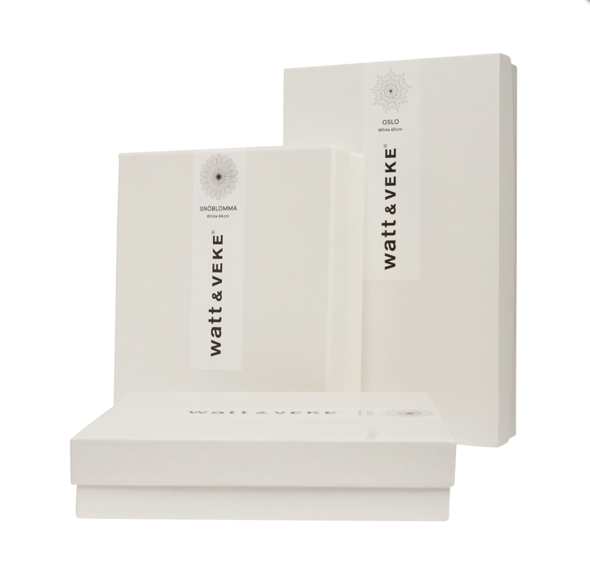 Three white rectangular boxes with minimalist “Watt & Veke” labels, containing Star Eldig in Paper in White (52 cm), are stacked at various angles against a plain white background.