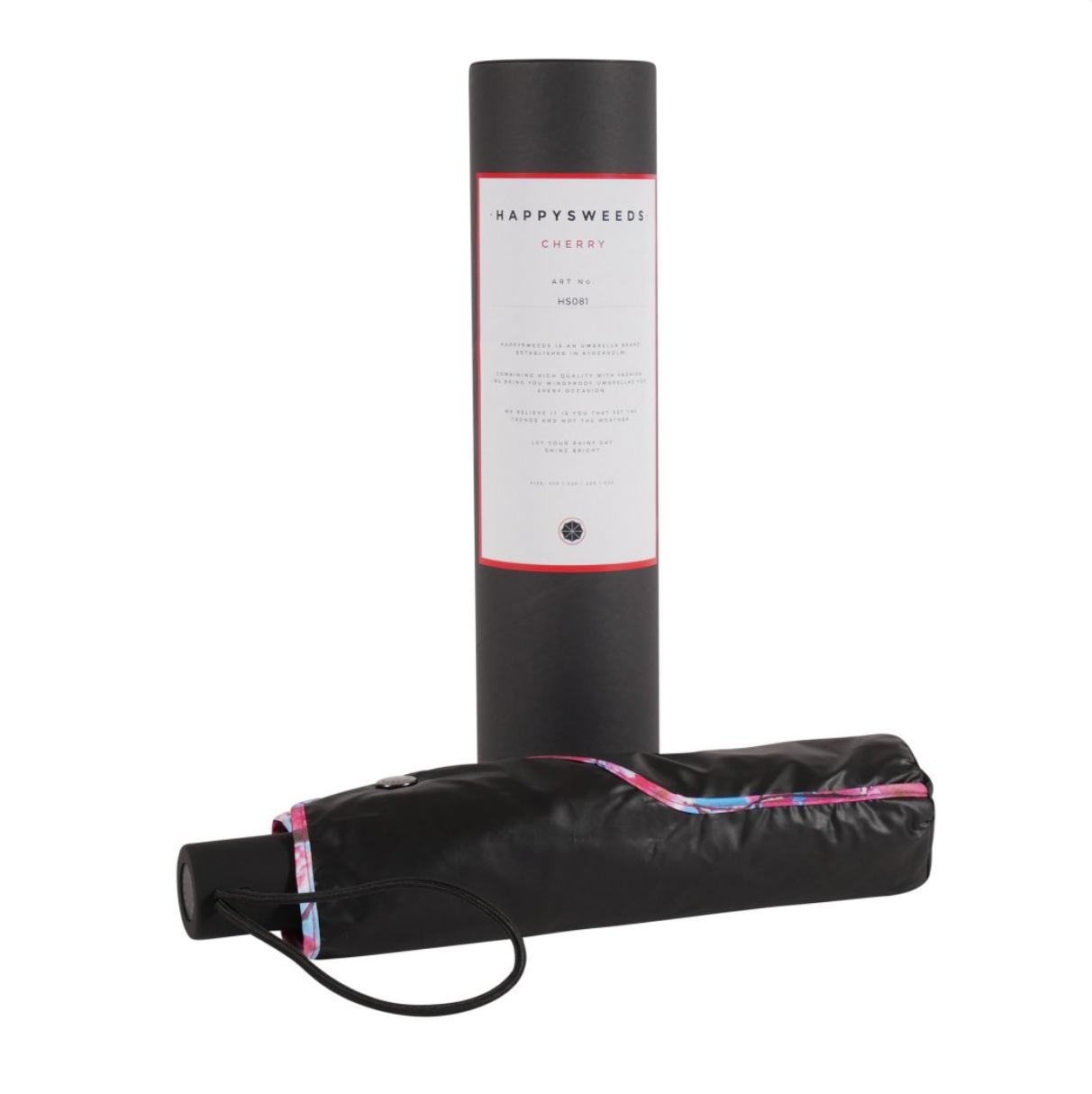 The Happysweeds Umbrella Cherry, a compact umbrella with a patterned trim and wrist strap, is displayed in front of its black HAPPYSWEEDS CHERRY packaging. This automatic umbrella offers stylish, on-the-go protection.
