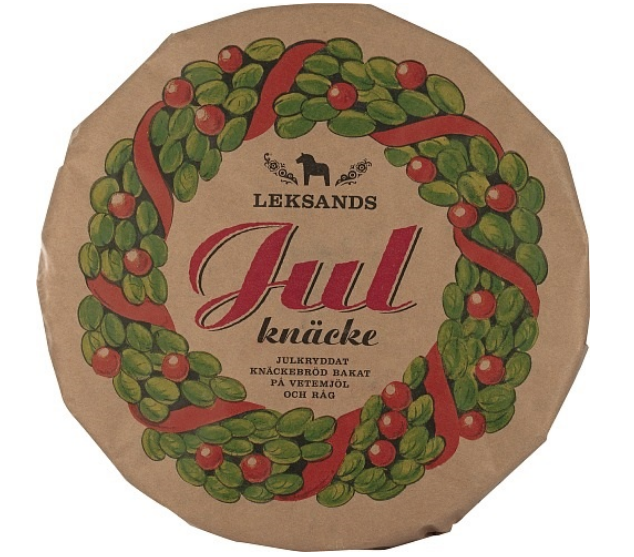 A round 530g package of Deli Leksands Julknäcke – Christmas Crispbread, featuring a green and red wreath with festive lettering on a brown background.