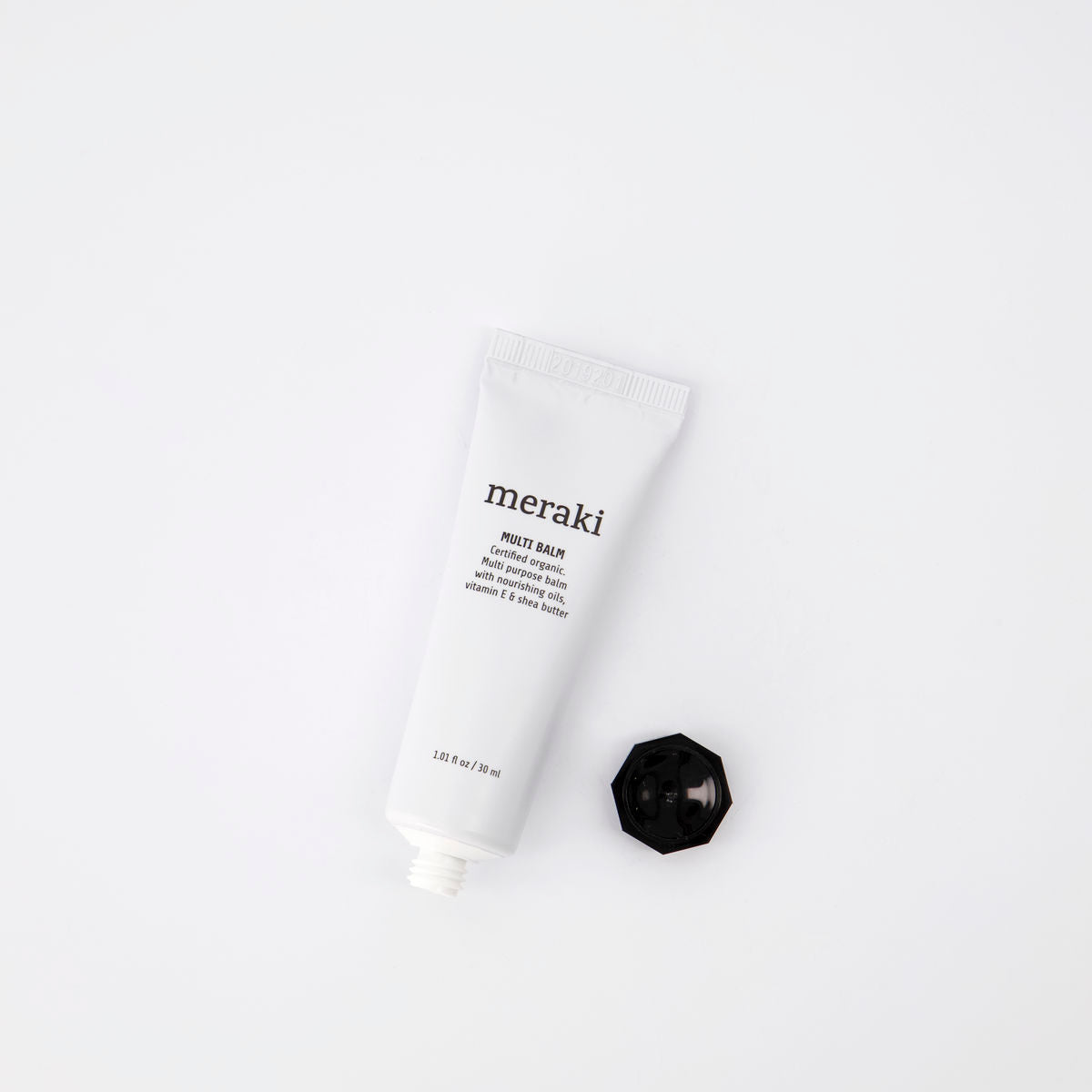 A white tube of Meraki Organic Multi Balm for Moisturising Dry & Damaged Skin (30 ml) with a black screw cap is placed beside it on a white background, perfect for hydrating and repairing dry or damaged skin.