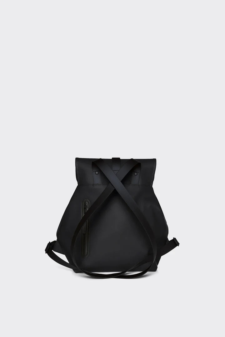 The Rains Bucket Backpack in Black by Rains is made from weatherproof PU fabric, with a top flap closure, external zip pocket, and crossed shoulder straps, shown against a plain light background.