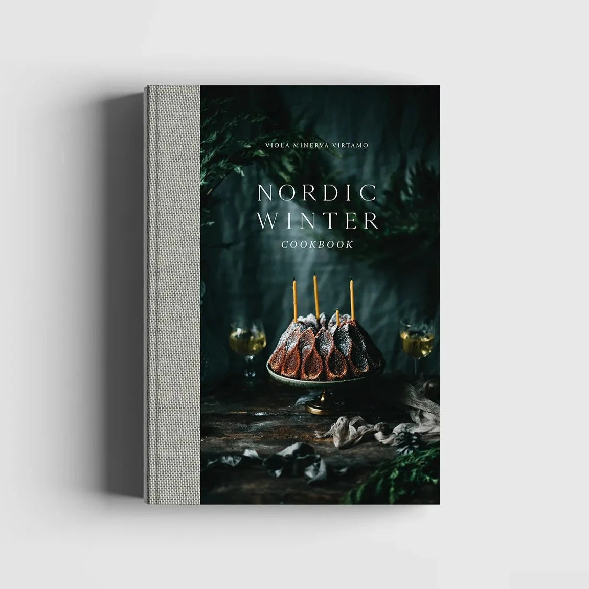 Nordic Winter - Cook Book by Cozy Publishing features a cover with a powdered sugar bundt cake, greenery, and two glasses—ideal for fans of Nordic winter recipes and Finnish Christmas cuisine.
