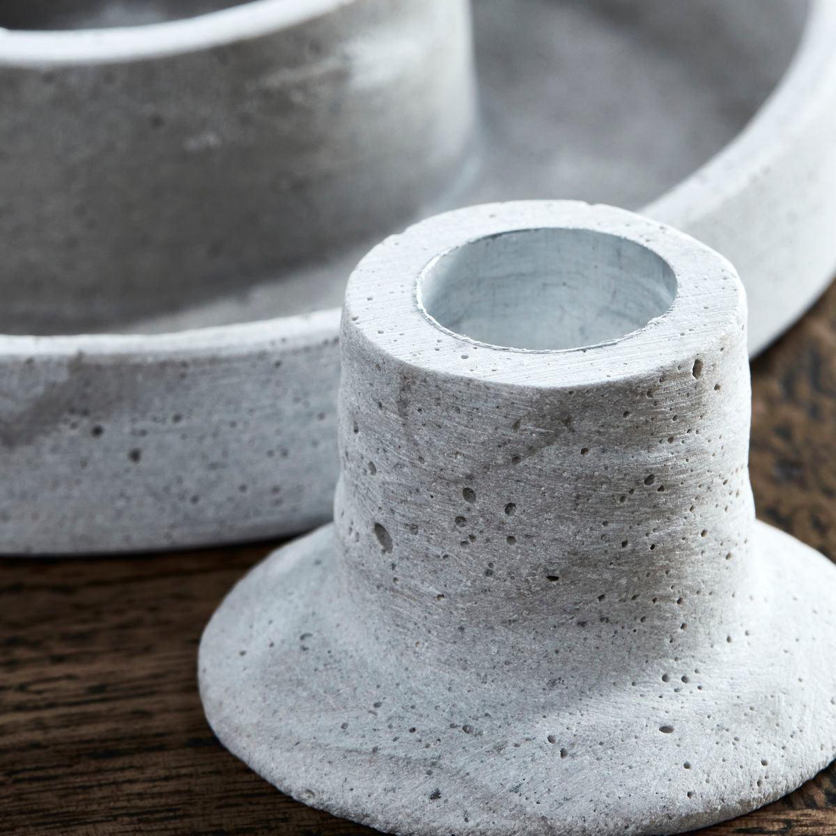 Close-up of the House Doctor Candle Stand Daca, 2 in 1, Cement Look (15cm) on a wooden surface, with another similar piece in the background—ideal for industrial-style decor.