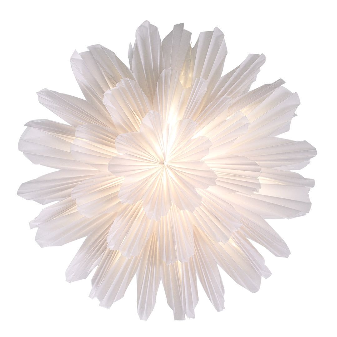 The Star Snöblomma Christmas White 44cm by Watt & Veke features a white, pleated tracing paper shade with a radial floral design, illuminated from within and photographed from above.